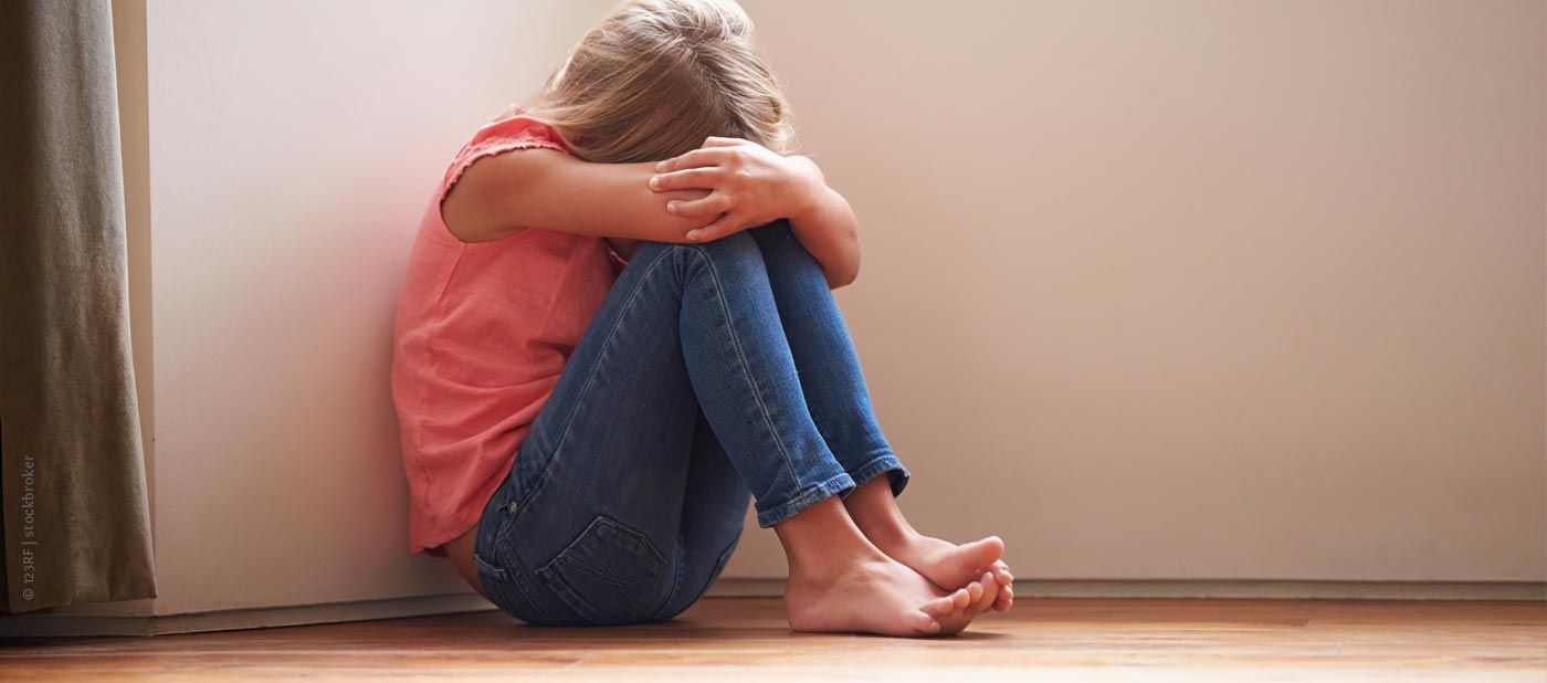 AK Missbrauch vom Kinderschutzbund Kempen e.V., Foto: Mädchen sitzt traurig auf dem Boden an Wand gelehnt